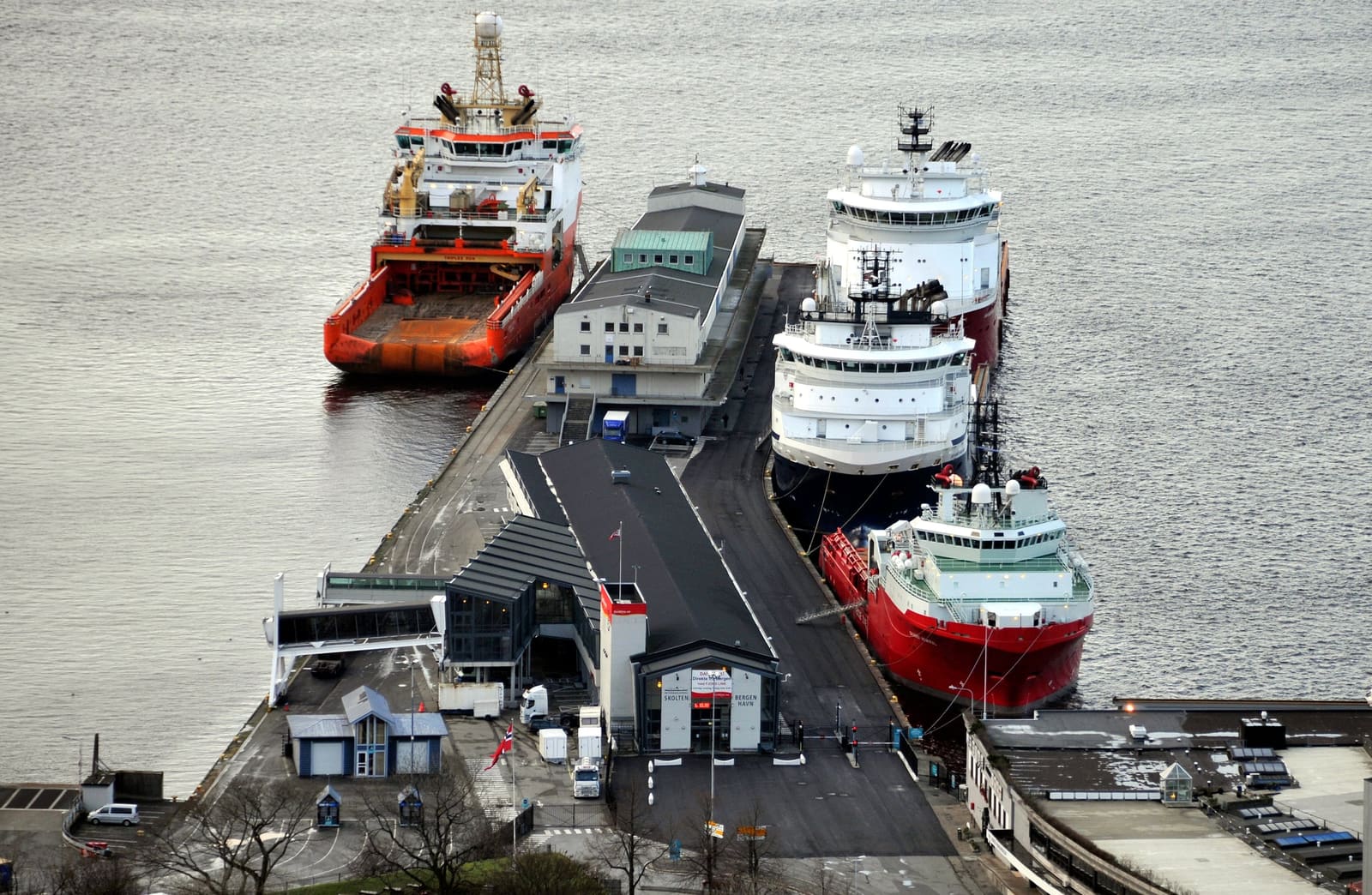 Four offshore vessels alongside a pier, seen from above, with the quay buildings between them.